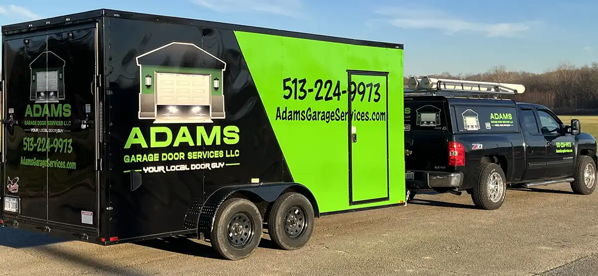 A photo of a black and green pickup truck and trailer that belongs to a garage door repair company named Adams Garage Door Services LLC.